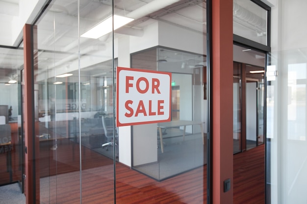 Графическое фоновое изображение красного знака «Продажа» на стеклянной двери офисного здания, копией пространства