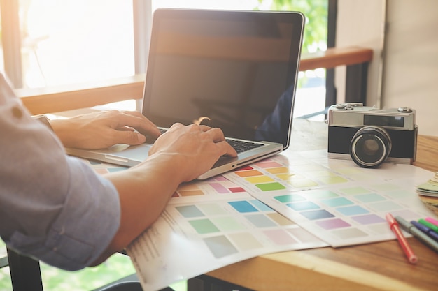 写真 机の上にグラフィックデザインと色見本とペン。