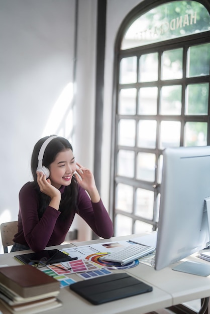 Foto graphic designer donne freelance che indossano le cuffie per ascoltare musica per rilassarsi dopo aver disegnato il logo del marchio e lavorare alla progettazione di graphic design con attrezzature tecnologiche in studio a casa