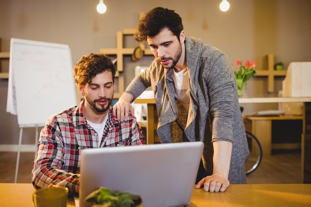 Graphic designer using laptop with his coworker