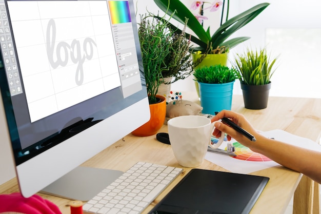 Photo graphic designer using pen tablet to design a logo.