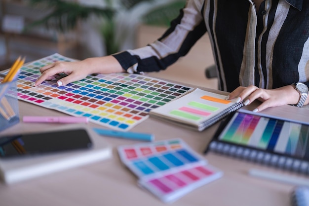 Женщины-графические дизайнеры выбирают цвет в образцах цветов и работают над графическим дизайном бренда.