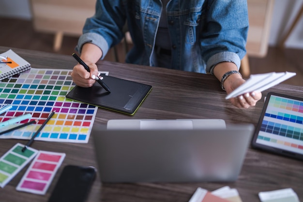 グラフィック デザインをデザインするために色を選択しながら、デジタル タブレットで作業するグラフィック デザイナーの女性