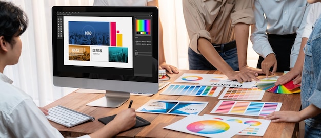 グラフィックデザイナーは、現代のデジタルスタジオの職場でプロのグラフィックチームとユニークなデザインをブレインストーミングしながら、ラップトップコンピューターとグラフィック描画ペンで作業しますパノラマショットを精査します
