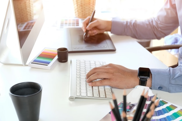 Graphic designer working on computer while using graphic tablet at desk in the office