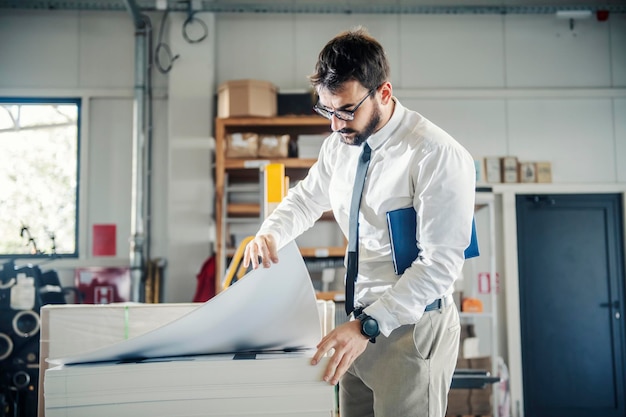 A graphic engineer looking at sheets and proofs at printing shop