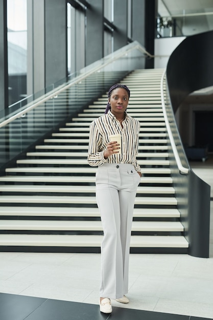 Графический портрет в полный рост уверенной афро-американской бизнес-леди, смотрящей в камеру, позируя в офисном зале