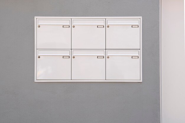 Photo graphic view of white mailboxes on a grey wall of a house