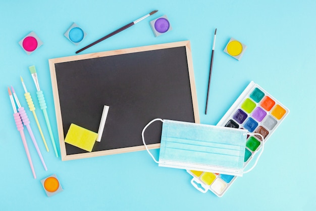 Graphite board with chalk and stationery around with medical protective mask