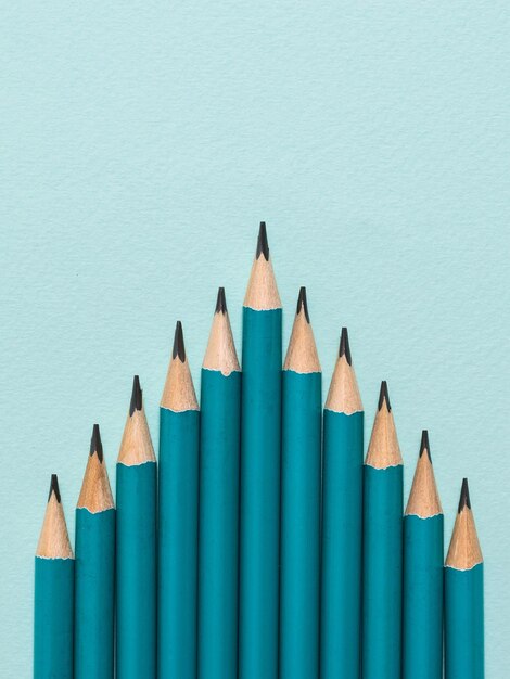 Graphite pencils on a blue background laid in the form of a pyramid