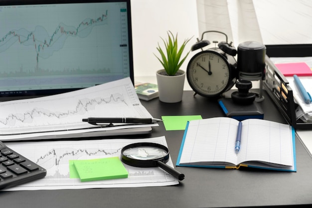 Photo graphs of movement of financial instrument on white sheet of paper magnifying glass on graph laptop