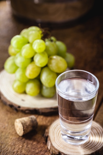 Foto grappa o graspa è un brandy a base di uva. vetro con bevanda alcolica e uva accanto