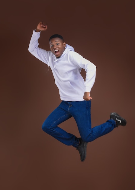 Grappig Afrikaans mannelijk model poseren met een verbaasde glimlach binnenfoto van een sportieve zwarte man die springt
