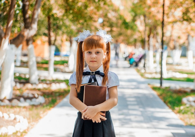 Grappig charmant meisje met boeken in haar handen, op de eerste schooldag of kleuterschool.