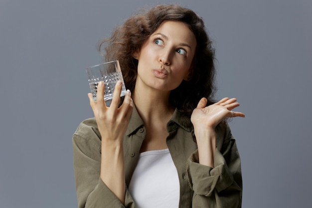 Grappig dromen krullend mooie vrouw in casual kaki groen shirt houden glas water stuur kus poseren geïsoleerd op over grijze blauwe achtergrond Gezonde levensstijl Water is leven concept Kopieer ruimte