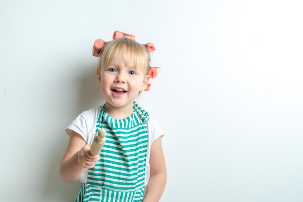 grappig emotioneel kind in de rol van een boze vrouw in krulspelden en een keukenschort