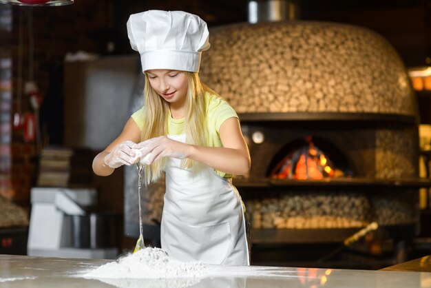 Grappig gelukkig chef-kok meisje koken bij restaurant keuken