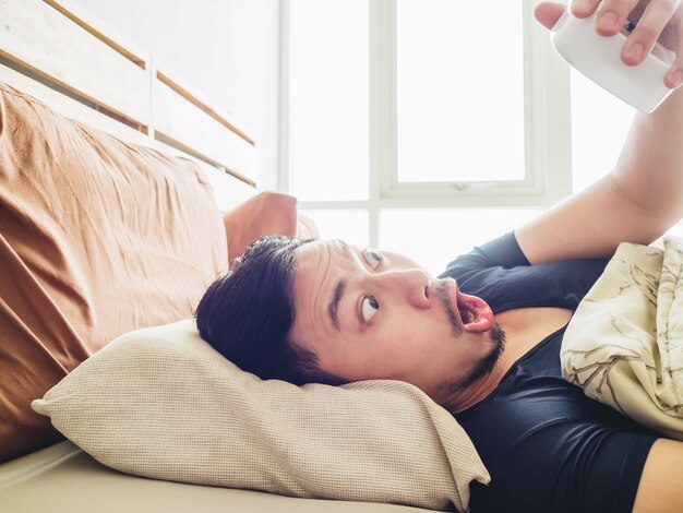 Grappig gezicht aziatische man geschrokken als hij laat wakker wordt voor een afspraak.