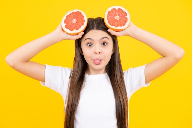 Grappig gezicht Tienermeisje met grapefruit Vitamine en fruit Kind eet sinaasappel