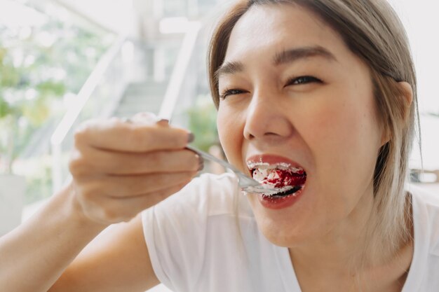 Grappig gezicht van een gelukkige vrouw die zorgeloos taart eet in het café.