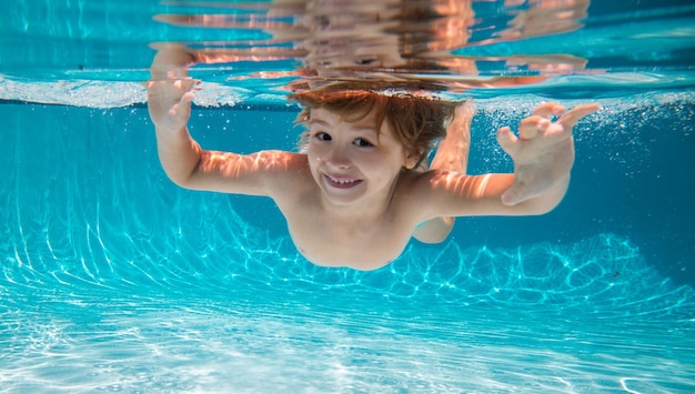 Grappig gezichtsportret van een kind dat onder water zwemt en duikt met plezier in het zwembad