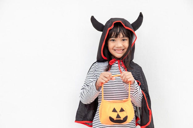 Grappig Halloween Kid Concept, klein schattig meisje met kostuum Halloween spook eng hij houdt oranje pompoenspook bij de hand, op witte achtergrond