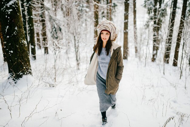 Grappig jong aantrekkelijk meisje met een tulband uit de sjaal wandelen in het sneeuwwoud