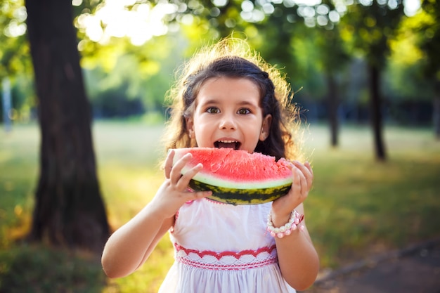 Grappig jong geitje die watermeloen in openlucht in de zomerpark eten, nadruk op ogen. Kind, baby, gezond eten.