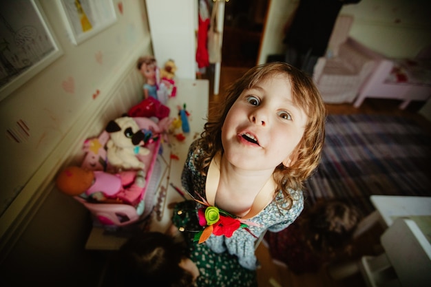 Grappig kind dat naar de camera kijkt in de kinderkamer