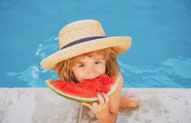 Grappig kind speelt in het zwembad het kind eet een zoete watermeloen geniet van de zomer zorgeloze kindertijd