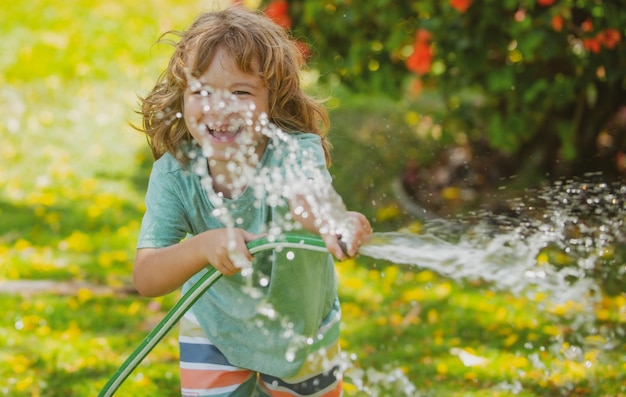 Grappig kind speelt met tuinslang in achtertuin kind heeft plezier met waternevel in de zomer buiten