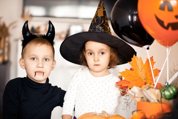 Grappig kindmeisje en jongen in heksen- en kwade kostuums voor Halloween hebben plezier.