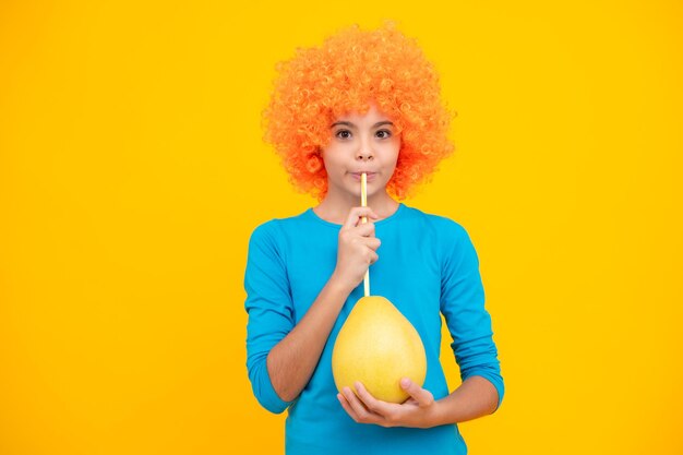 Grappig kindmeisje met pruik houdt grote citrusvruchten pummelo of pomelo vol vitamine gezonde kinderen aan het eten