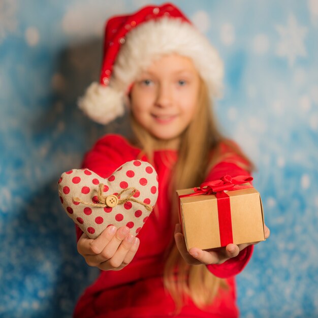 Grappig klein meisje in schattige rode kerstmuts houdt geschenkdoos met procent voor haar gezicht. Kerst verkoop concept.