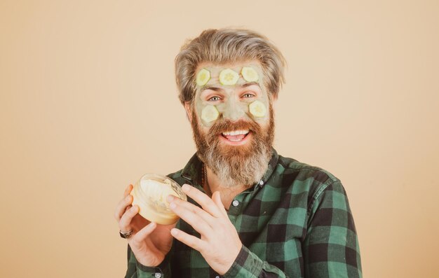 Grappig mannelijk model met masker en plakjes komkommer op face spa dermatologie wellness en gezichtsbehandeling