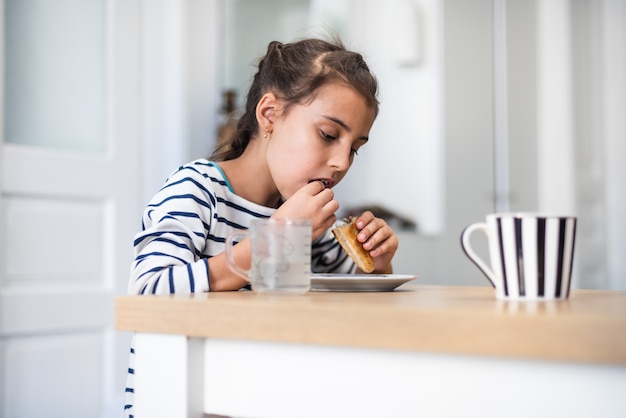 Grappig meisje dat met de hand gemaakt koekje eet