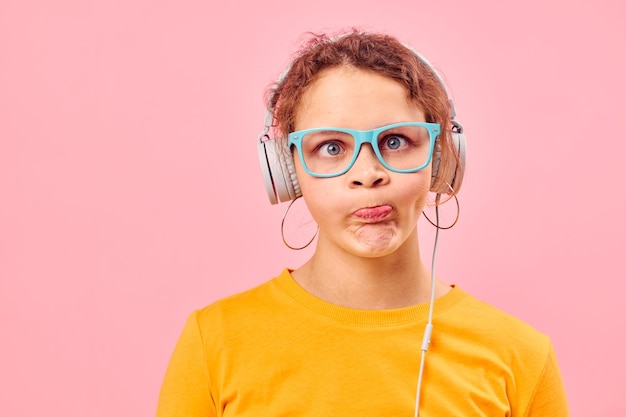 Grappig meisje geel tshirt hoofdtelefoon entertainment muziek plezier roze achtergrond ongewijzigd