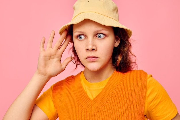 Grappig meisje in een oranje trui in gele hoed handgebaar bijgesneden weergave ongewijzigd