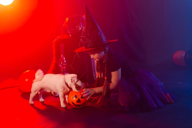 Grappig meisje kind kind in halloween kostuum heks spelen met spookachtige jack pompoenen mist en jack