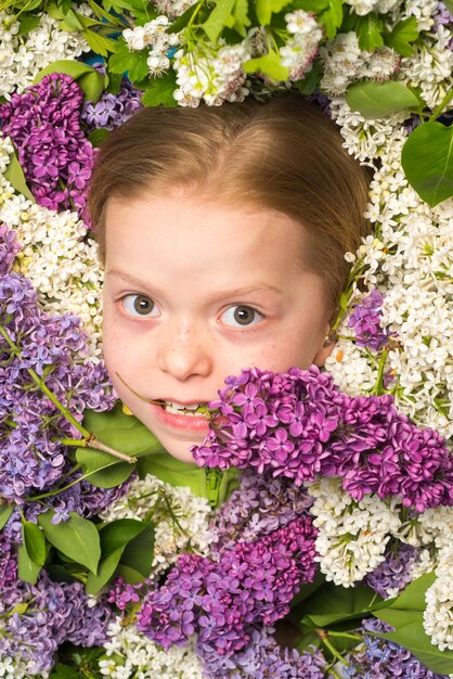 Grappig meisje met bloemen in een bloeiende zomertuin Tienermeisje met een boeket van paarse en witte lila