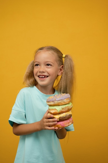 Grappig meisje met donuts op een gele achtergrond