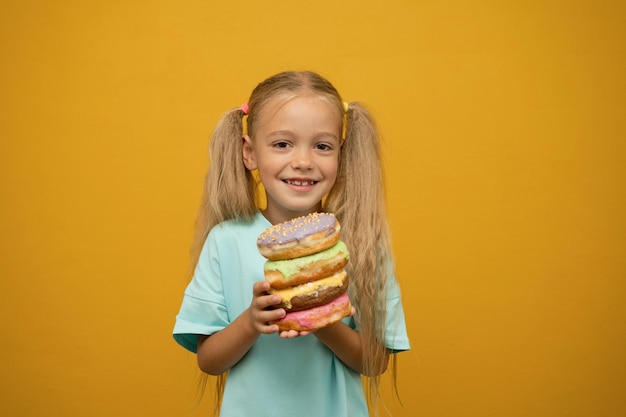 Grappig meisje met donuts op een gele achtergrond