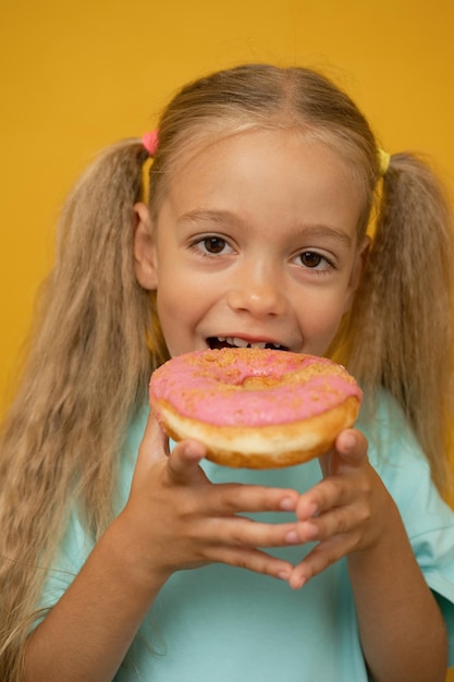 Grappig meisje met donuts op een gele achtergrond