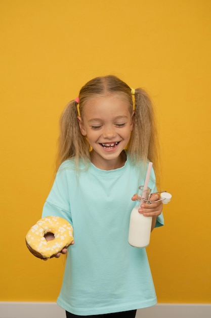 Grappig meisje met donuts op een gele achtergrond