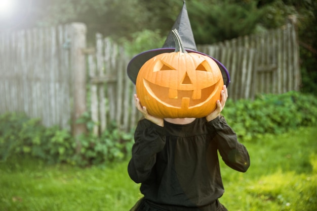 Grappig meisje met halloween-pompki in tuin