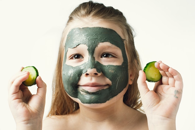 Grappig meisje met klei kosmetisch masker in badhanddoek