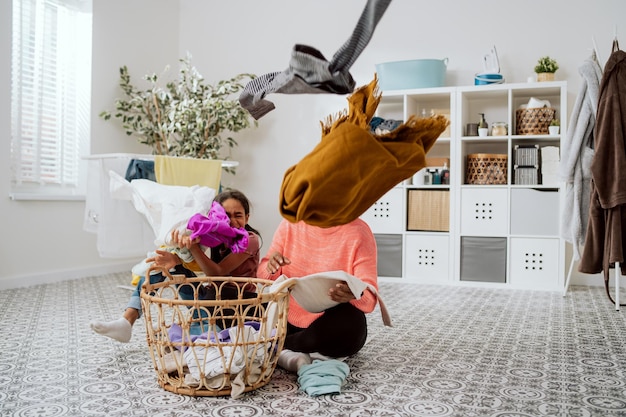 Grappig meisje stoort moeder die de was doet in de badkamer en wil tijd met vrouw doorbrengen