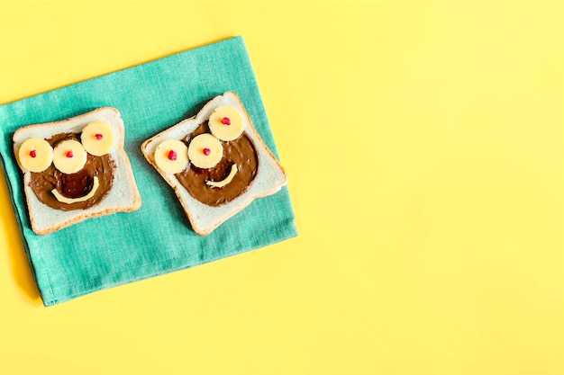 Grappig monstergezicht op halloween sandwich toast brood met pindakaas kaas op servet gele achtergrond kopie ruimte Kinderen kind zoet dessert ontbijt lunch eten