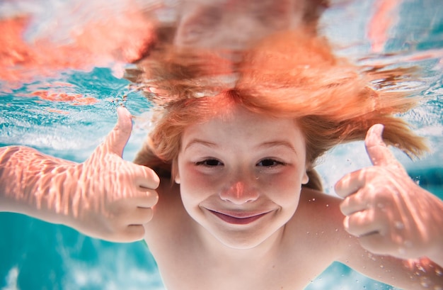 Grappig opgewonden kinderen gezicht onder water onder water kind in het zwembad schattig kind jongen zwemmen in