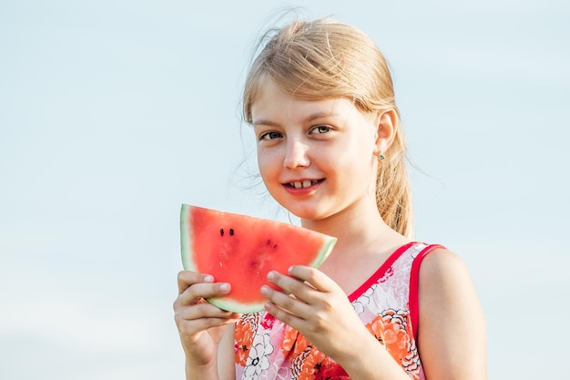 Grappig portret van aanbiddelijk blondemeisje die watermeloen in openlucht eten